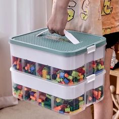 a person holding a plastic container filled with lots of colorful legos on it's side