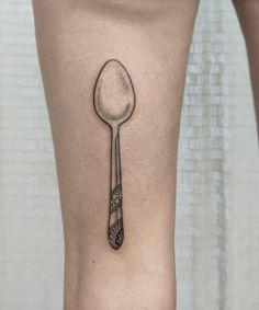 a spoon and fork tattoo on the side of a woman's leg, which is black and white