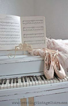 a white piano with ballet shoes and sheet music