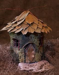 a birdhouse with leaves on the roof and grass growing all over it's sides