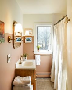 a bathroom with pink walls and white curtains