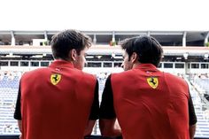 two men in red vests looking out over the bleachers at a stadium