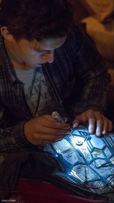 a young man sitting on the floor looking at an electronic device