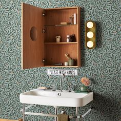 a bathroom sink sitting under a mirror next to a wall mounted cabinet with lights on it