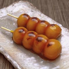 four skewers of food sitting on top of a piece of parchment paper with toothpicks sticking out of them