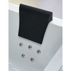 a black towel hanging on the side of a white bathtub with four knobs