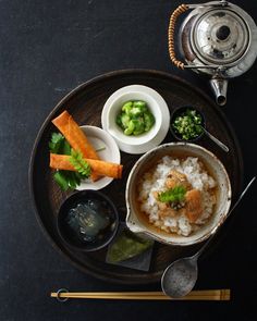 a plate with rice, broccoli and carrots on it next to a silver teapot