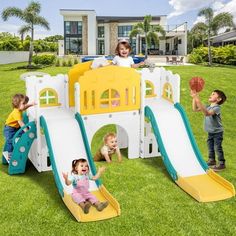 three children playing in the yard with their slide and basketballs on green grass near a large house