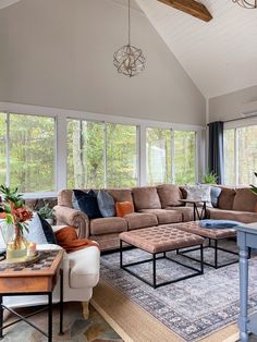 a living room filled with furniture and windows covered in lots of natural light from the large windows