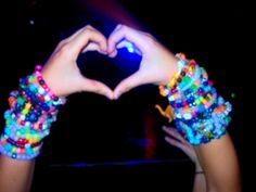 two hands in the shape of a heart with beaded bracelets on their wrists