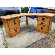 a wooden desk sitting on top of a sidewalk next to a black car in the background