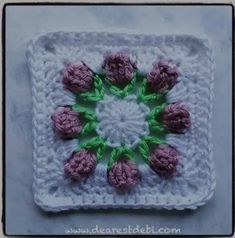 a crocheted square with pink flowers on it