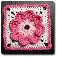 a crocheted square with a pink flower on the center and white squares around it