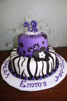 a purple and white birthday cake sitting on top of a wooden table