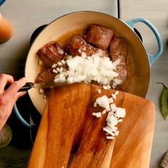 someone is cutting up some food in a pan on the table with chopping utensils