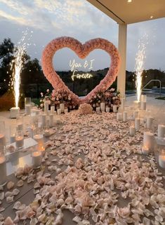 a heart - shaped sign is surrounded by flowers and candles