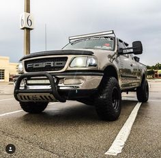 a silver truck parked in a parking lot next to a tall clock on a pole