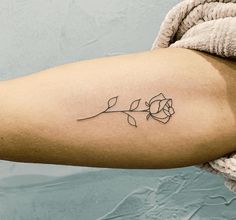 a woman's arm with a single rose tattoo on the left side of her arm