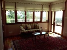 a living room filled with furniture and windows covered in blinds on top of wooden flooring