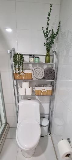 a white toilet sitting in a bathroom next to a shelf filled with towels and other items