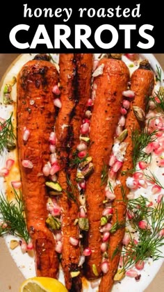 roasted carrots with pomegranate and herbs on a white plate next to a lemon wedge