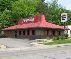 a pizza hut sitting on the side of a road next to a street sign that says, remember when you could dine in at pizza hut?