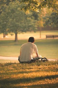 a man sitting on the ground next to a tree