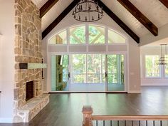 an empty living room with wood floors and stone fireplace