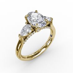 a three stone engagement ring with pear shaped diamonds on the shoulders and side stones in yellow gold