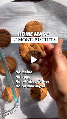 someone is holding some cookies in their hand and pointing to them with the words home made almond biscuits