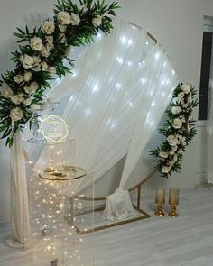 a white wedding arch decorated with flowers and greenery