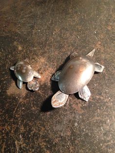 two metal turtles sitting on top of a table