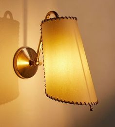 a lamp that is on the wall next to a light fixture with a shadow cast on it