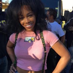 a woman standing in front of a bus with her hands on her hips and smiling at the camera