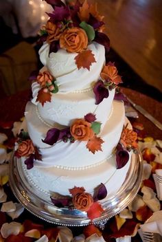 a three tiered white wedding cake with orange and purple flowers on the top layer