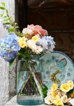 a vase filled with colorful flowers sitting on top of a table next to a plate