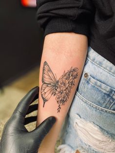 a woman's arm with a butterfly and flowers tattoo on the left side of her arm