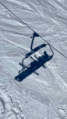 the shadow of a ski lift is cast on snow covered ground, as seen from above