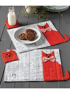 a table topped with two place mats covered in red cat appliques and cookies