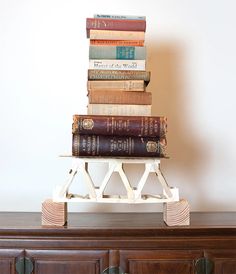 a stack of books sitting on top of a wooden dresser