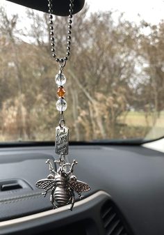 a car dashboard with a necklace hanging from it's center console and a bee charm attached to the dash board