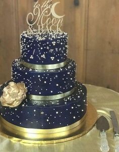 a blue and gold wedding cake on a table with two silver forks next to it