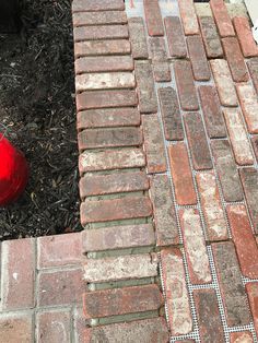 a red fire hydrant sitting next to a brick walkway