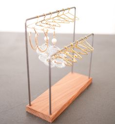 a wooden stand holding several pairs of earrings and earring hooks on it's sides