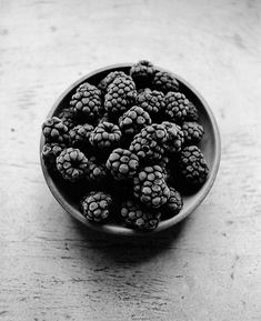 a bowl full of blackberries sitting on top of a table