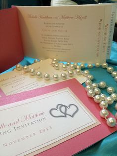 the wedding stationery is set up with pearls and a heart - shaped brooch