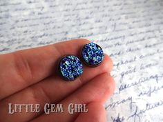 These faux blue druzy earrings are a show stopper! With every slight turn the druzy cabochon reflects a mired of sparkling blues and greens. Druzy cabochons are securely set in a 12mm earring tray, available in Antique Copper (shown), Bright Silver, Gunmetal, or Antique Bronze. Plated Brass, Lead Free And Nickel Free PRODUCTION TIME: Handmade and Made-to-Order so please allow approximately one week to make your jewelry before shipping. Your jewelry will not be the one shown, but will be made to Sparkling Blue Earrings For Gift, Glitter Round Jewelry As Gift, Glitter Round Earrings For Gifts, Round Glitter Jewelry As Gift, Round Glitter Jewelry For Gifts, Earring Tray, Galaxy Earrings, Mermaid Earrings, Druzy Earrings