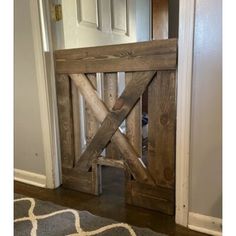 a wooden gate in the middle of a room with a rug on the floor next to it