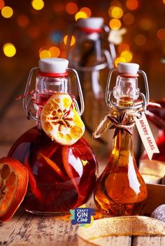 two bottles filled with liquid sitting on top of a wooden table next to sliced oranges