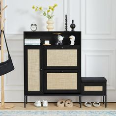 a black and beige cabinet sitting next to a white wall with flowers on top of it